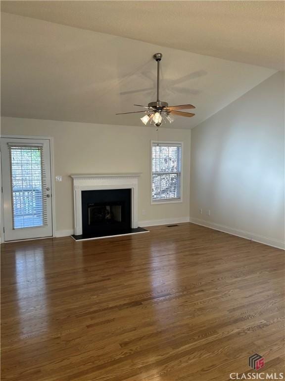 unfurnished living room with ceiling fan, dark wood-type flooring, vaulted ceiling, and a healthy amount of sunlight