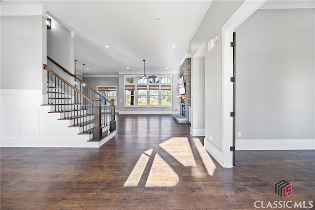 foyer featuring ceiling fan, dark hardwood / wood-style flooring, crown molding, and a fireplace