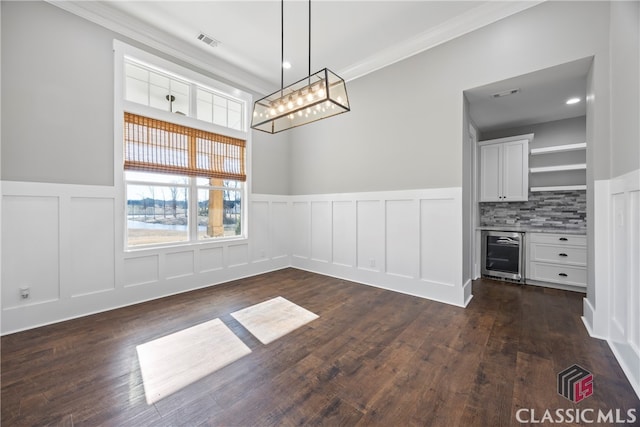 unfurnished dining area featuring ornamental molding, dark hardwood / wood-style flooring, and beverage cooler