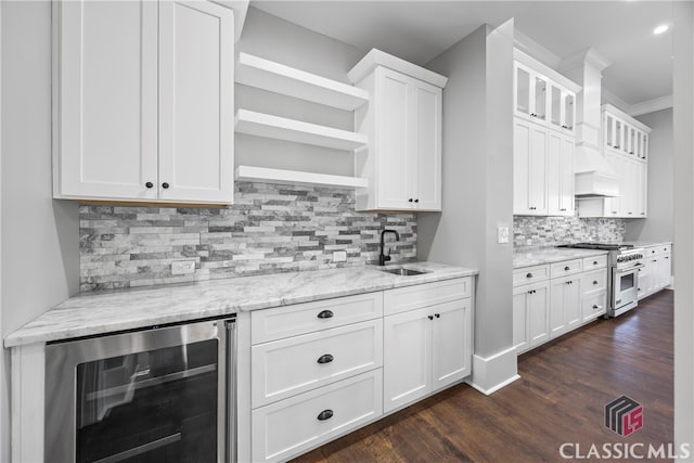 kitchen featuring beverage cooler, sink, white cabinetry, backsplash, and high end stainless steel range