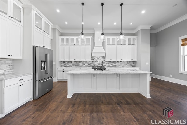 kitchen with decorative light fixtures, white cabinets, light stone counters, high quality fridge, and a center island with sink