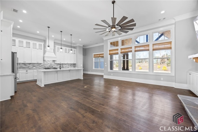 kitchen with hanging light fixtures, stainless steel fridge, a kitchen island with sink, white cabinets, and ceiling fan