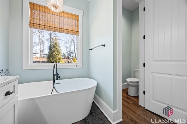 bathroom featuring a washtub, toilet, vanity, and hardwood / wood-style flooring