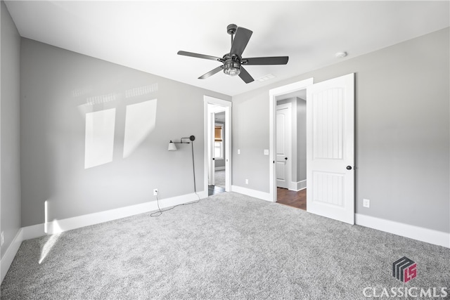 unfurnished bedroom featuring ceiling fan and dark carpet