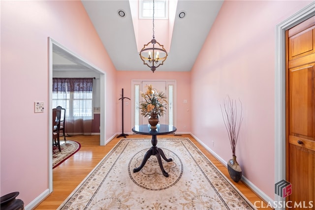 foyer featuring vaulted ceiling, light hardwood / wood-style flooring, and a chandelier