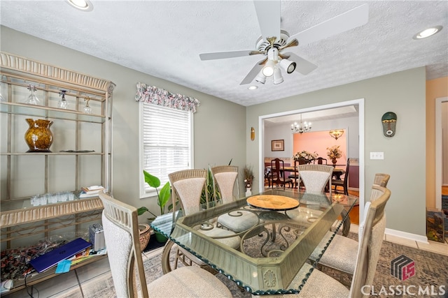 dining space with ceiling fan with notable chandelier, light tile patterned flooring, and a textured ceiling