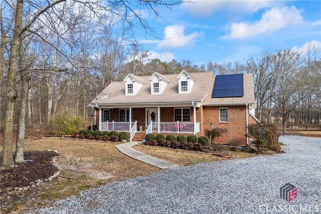 cape cod home with covered porch and solar panels