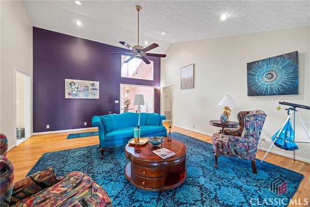 living room with high vaulted ceiling, a textured ceiling, ceiling fan, and hardwood / wood-style flooring