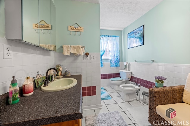 bathroom featuring sink, a bidet, a textured ceiling, tile walls, and toilet