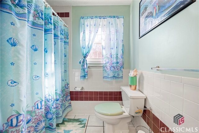 bathroom with toilet, tile patterned floors, and tile walls