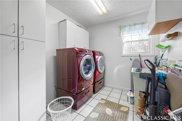 laundry area with independent washer and dryer, a textured ceiling, cabinets, and light tile patterned floors