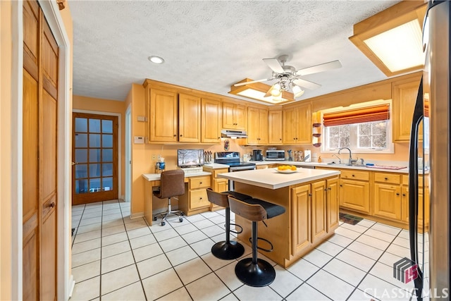 kitchen featuring appliances with stainless steel finishes, ceiling fan, a breakfast bar, a kitchen island, and light tile patterned flooring