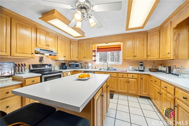 kitchen with a kitchen breakfast bar, stainless steel appliances, a center island, and light tile patterned floors