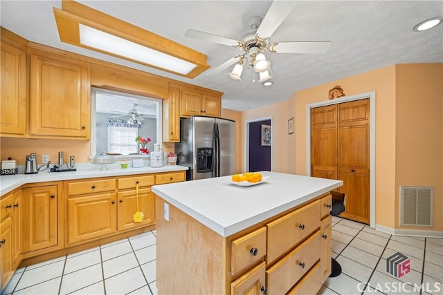 kitchen featuring a kitchen island, ceiling fan, stainless steel refrigerator with ice dispenser, and light tile patterned floors