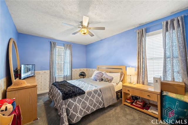 carpeted bedroom featuring a textured ceiling, ceiling fan, and wooden walls