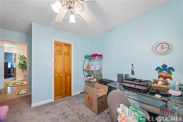 home office with a textured ceiling, light carpet, and ceiling fan