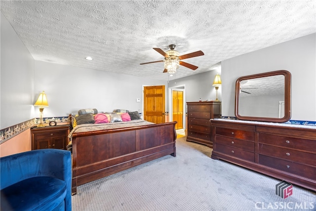 carpeted bedroom featuring ceiling fan and a textured ceiling