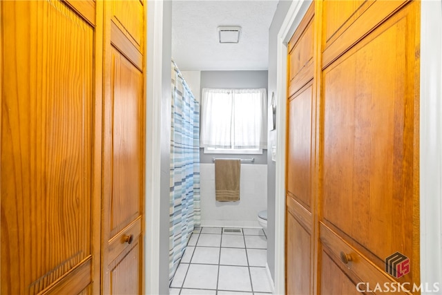 bathroom featuring a textured ceiling, tile patterned floors, and toilet