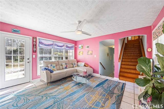 living room with ceiling fan, a textured ceiling, and light tile patterned floors