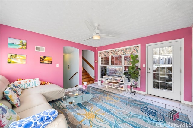 tiled living room featuring a textured ceiling and ceiling fan