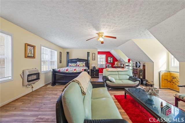 bedroom with heating unit, ceiling fan, hardwood / wood-style flooring, a textured ceiling, and lofted ceiling