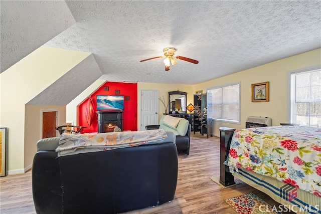 bedroom with ceiling fan, light hardwood / wood-style flooring, lofted ceiling, and a textured ceiling