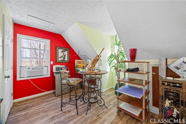 interior space with a textured ceiling, hardwood / wood-style floors, cooling unit, and lofted ceiling