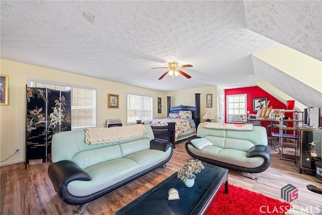 living room featuring lofted ceiling, wood-type flooring, a textured ceiling, and ceiling fan