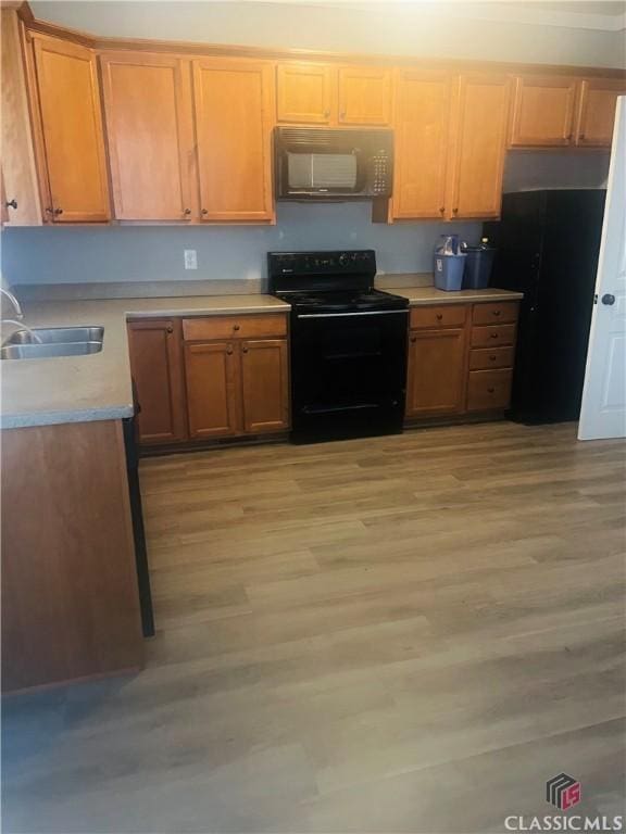 kitchen with sink, light hardwood / wood-style floors, and black appliances