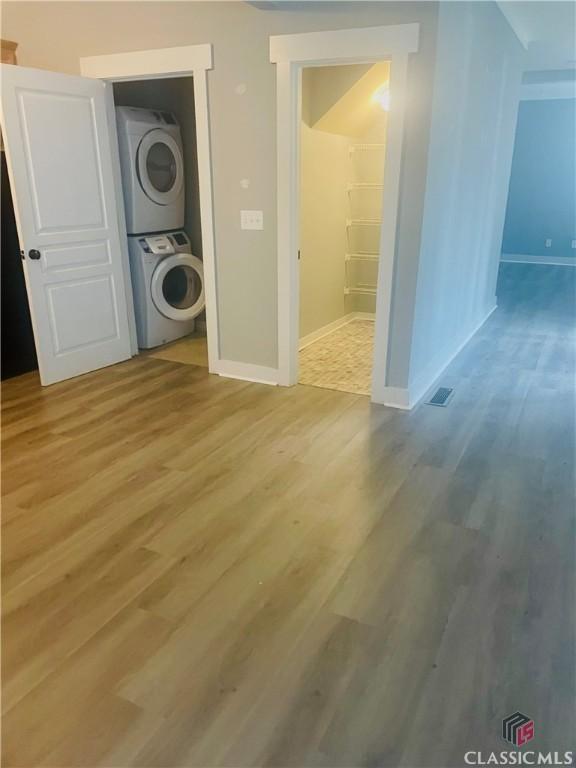 washroom featuring light hardwood / wood-style flooring and stacked washer / dryer