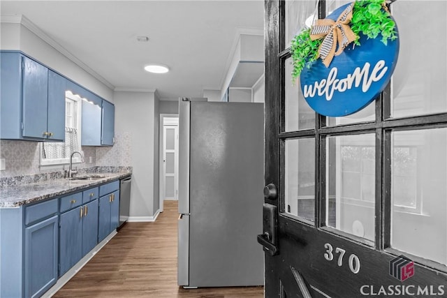 kitchen featuring stainless steel appliances, blue cabinetry, sink, and backsplash