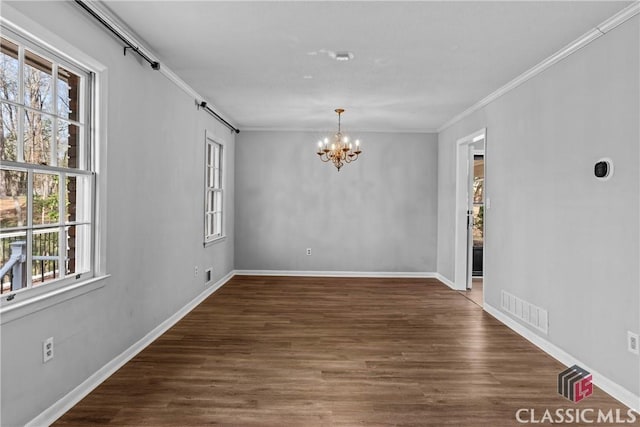 unfurnished room with dark wood-type flooring, an inviting chandelier, and crown molding