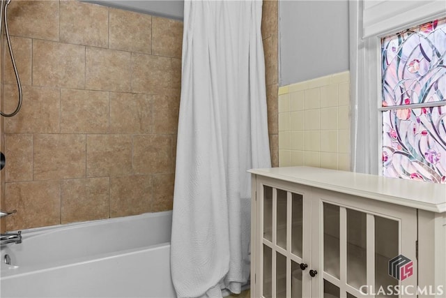 bathroom with tile walls and shower / bath combo