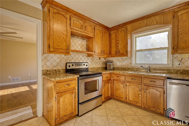 kitchen with sink, stainless steel appliances, a textured ceiling, and light tile patterned floors