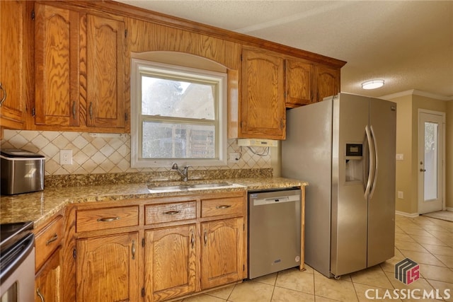 kitchen with sink, a textured ceiling, light tile patterned flooring, tasteful backsplash, and appliances with stainless steel finishes