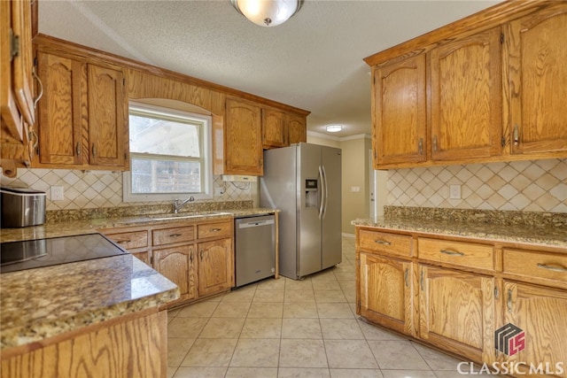 kitchen with a textured ceiling, light tile patterned floors, appliances with stainless steel finishes, ornamental molding, and sink