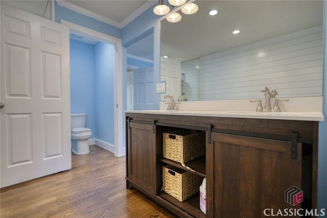 bathroom featuring sink, toilet, hardwood / wood-style flooring, and crown molding