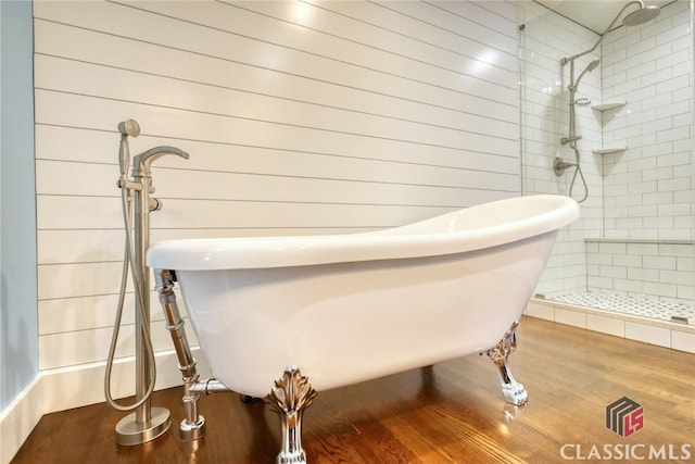 bathroom featuring independent shower and bath, hardwood / wood-style floors, and wood walls