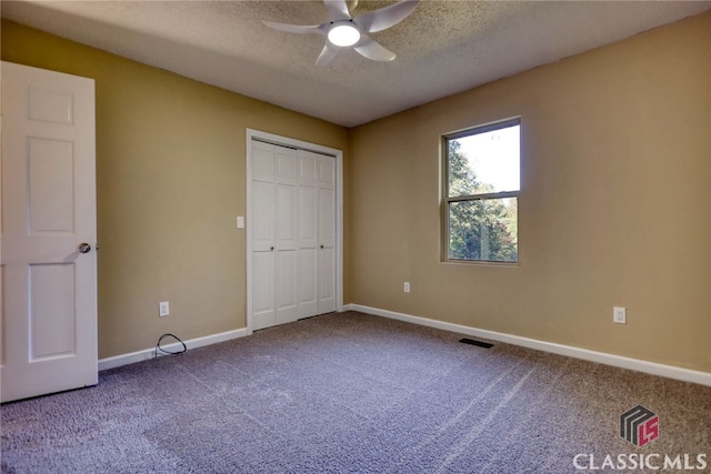 unfurnished bedroom featuring carpet flooring, a textured ceiling, ceiling fan, and a closet