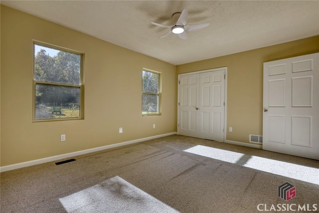 unfurnished bedroom featuring a closet, ceiling fan, carpet flooring, and multiple windows