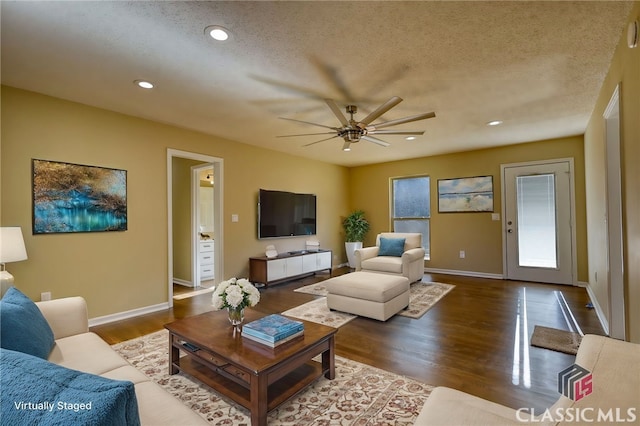 living room with a textured ceiling, ceiling fan, and dark hardwood / wood-style floors