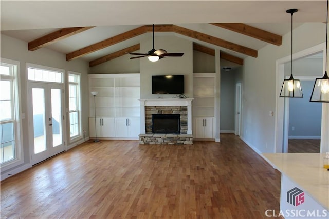 unfurnished living room with a stone fireplace, wood-type flooring, lofted ceiling with beams, ceiling fan, and built in shelves