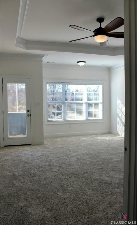 empty room with carpet, ceiling fan, a tray ceiling, and ornamental molding