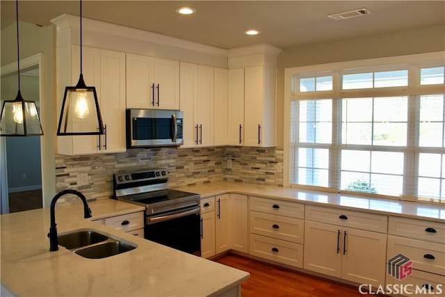 kitchen featuring stainless steel appliances, white cabinetry, hanging light fixtures, and sink