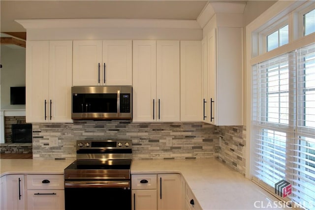 kitchen with white cabinets, stainless steel appliances, light stone countertops, and tasteful backsplash