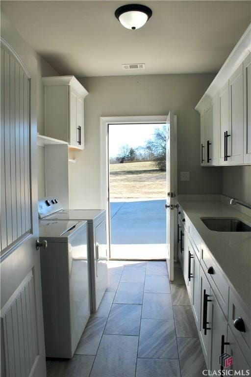 laundry room with light tile patterned flooring, cabinets, separate washer and dryer, and sink