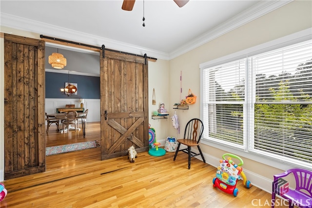 game room with ceiling fan, wood-type flooring, ornamental molding, and a barn door