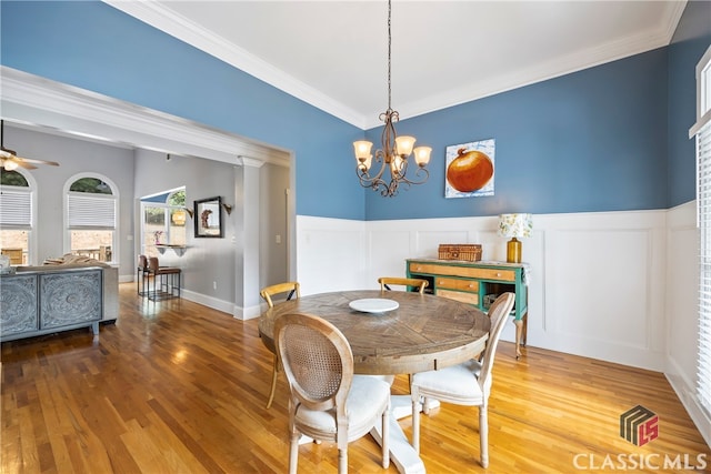 dining space with wood-type flooring, ceiling fan with notable chandelier, and crown molding