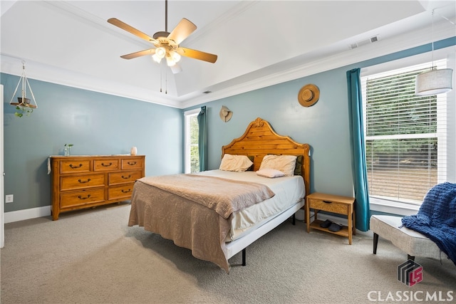 carpeted bedroom with ceiling fan, a raised ceiling, and crown molding