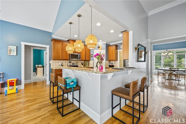 kitchen with decorative light fixtures, tasteful backsplash, kitchen peninsula, a notable chandelier, and a breakfast bar